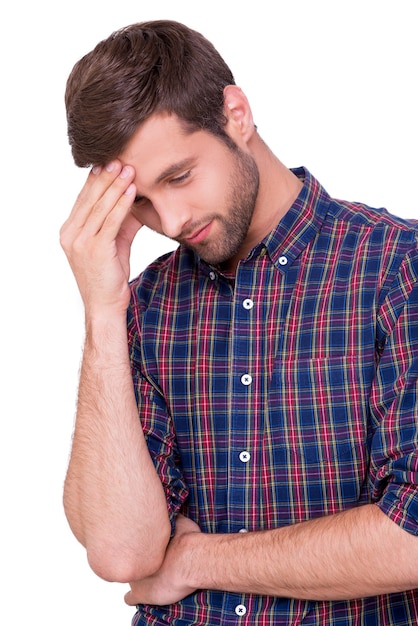 Encore raté. Jeune homme frustré en chemise décontractée touchant son front avec la main et gardant les yeux fermés tout en se tenant isolé sur blanc