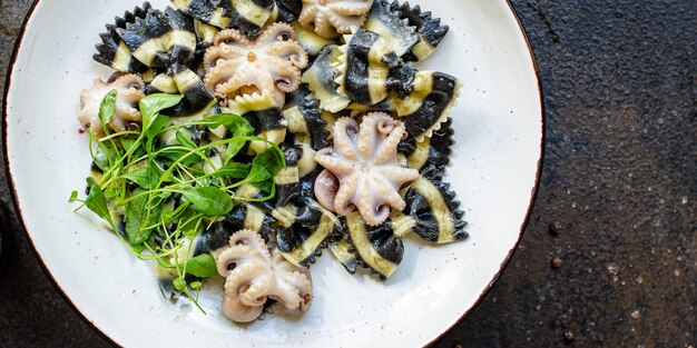 Encre de pâtes farfalle de fruits de mer de seiche avec bébé poulpe petits poulpes deuxième cours sur la table