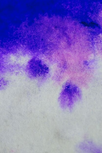 Encre violette étalée et absorbée sur papier gros plan blanc. Abstrait. Les taches d'encre se sont propagées et absorbées dans la macro de papier.