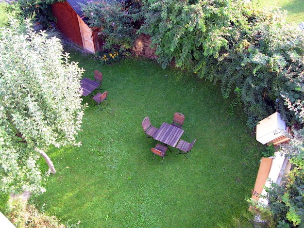 Endroit confortable pour se détendre, vue de dessus. Pelouse verte, plantes à fleurs autour, table et chaises en bois