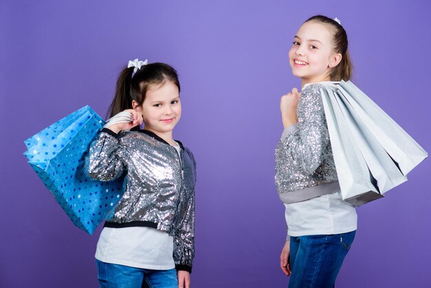 Endroit passionnant pour faire du shopping Shopping et achat Vendredi noir Vente et remise Journée shopping Les enfants détiennent des paquets de tas Mode pour enfants Filles soeurs amis avec des sacs à provisions fond violet