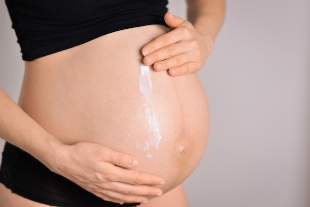 Enduire de crème hydratante sur le ventre d'une femme enceinte