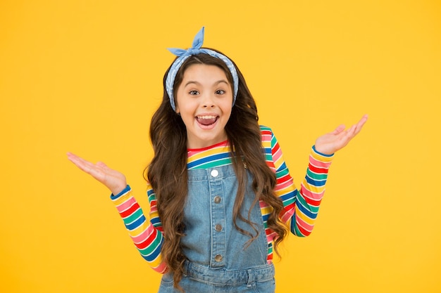 Enfance heureuse fille rétro geste gai vacances d'été joie petit enfant fond jaune mode enfant à l'ancienne petite beauté mouchoir cheveux longs style vintage modèle de mode rétro