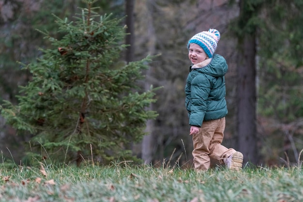 Enfant de 34 ans se promène en forêt à l'automne Joli enfant en bonnet tricoté et veste bologne dans la forêt de pins par une froide journée d'automne