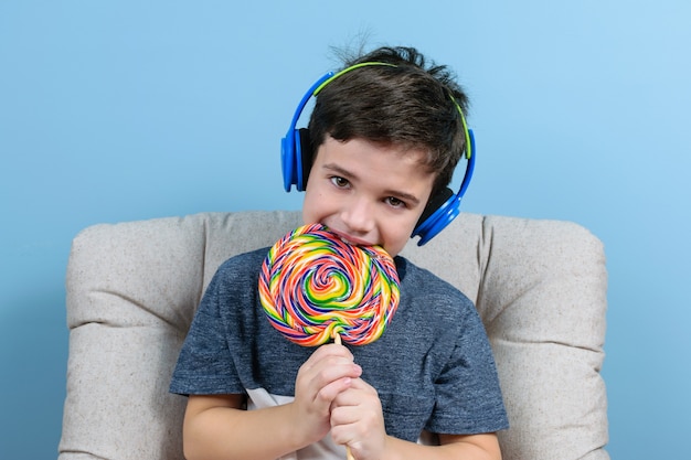 Enfant de 8 ans avec casque et mordant une grosse sucette colorée.