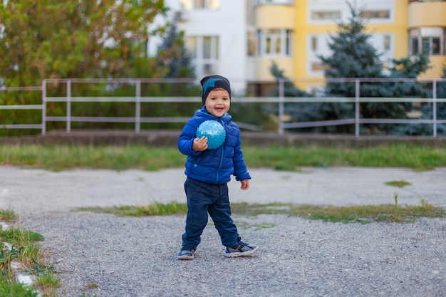 Enfant actif dans une veste avec un ballon dans les mains