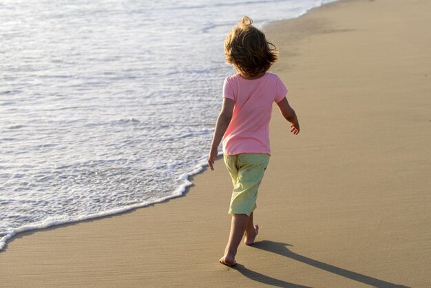 Enfant actif s'amusant pendant les vacances d'été enfant garçon courant sur la plage de sable