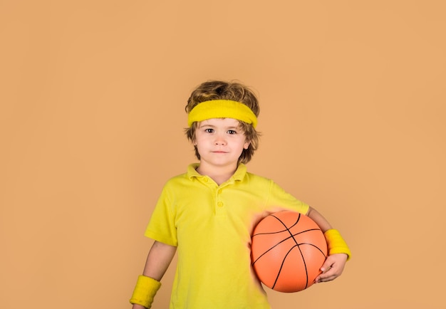 L'enfant actif de sport tient le garçon sportif de basket-ball avec le garçon de boule dans le sport de concept de sport de passe-temps de vêtements de sport