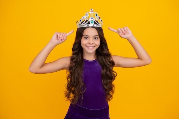 Enfant adolescent en couronne de reine isolé sur fond jaune Princesse fille en diadème Adolescente porter diadème Bonne fille face à des émotions positives et souriantes