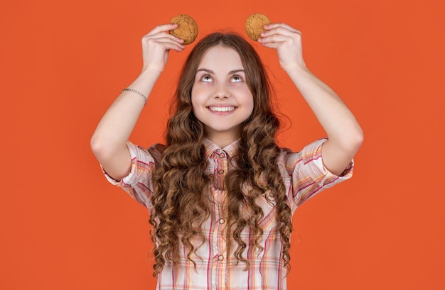 Enfant adolescent heureux avec des biscuits à l'avoine sur fond orange