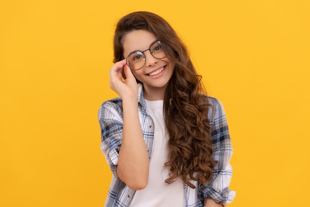 Enfant adolescent heureux en chemise à carreaux et lunettes sur fond jaune