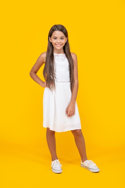 enfant adolescent heureux en robe blanche debout sur fond jaune
