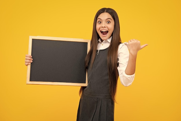 Enfant adolescent tenant un tableau blanc pour le message Isolé sur un fond jaune Texte vide