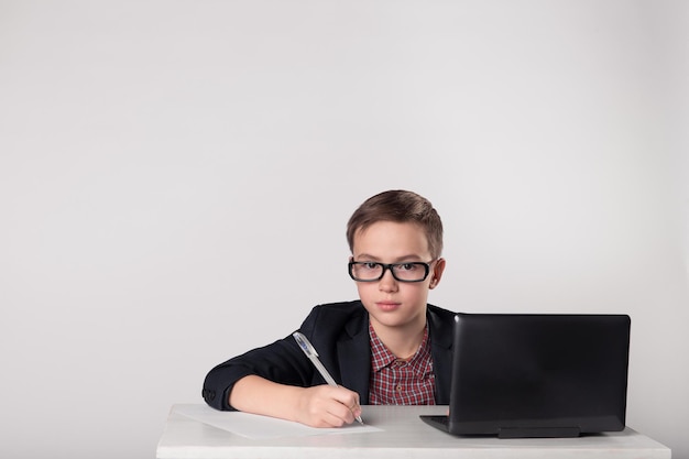 Enfant d'affaires en lunettes écrivant avec un stylo