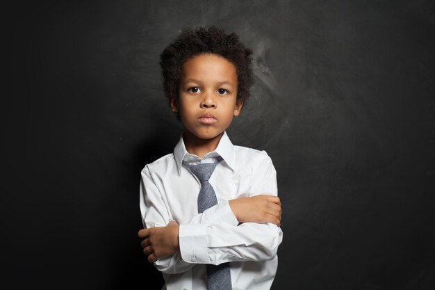 enfant afro-américain étudiant garçon avec les bras croisés sur noir