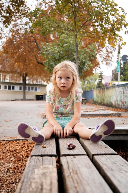 Photo une enfant d'âge préscolaire blonde est assise sur un banc.