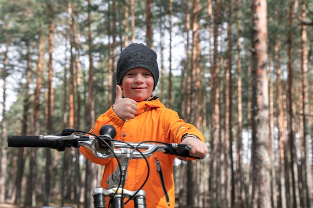 Un enfant d'âge préscolaire heureux fait du vélo dans le parc sur une piste cyclable