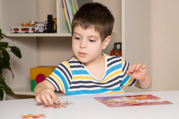 Un enfant d'âge préscolaire joue à des puzzles et rassemble une image