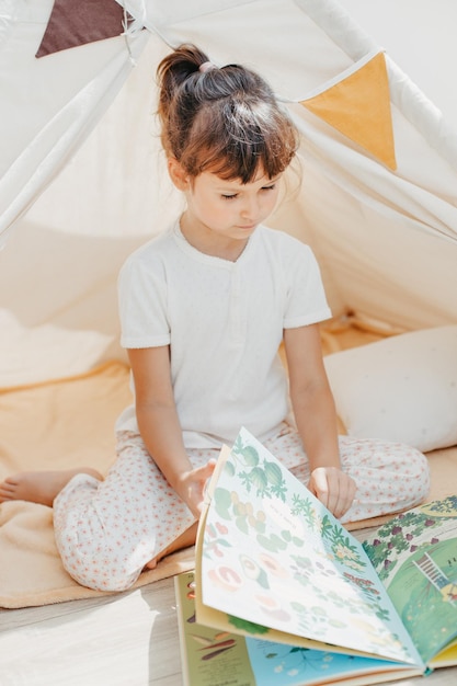 Enfant d'âge préscolaire lisant un livre à la maison