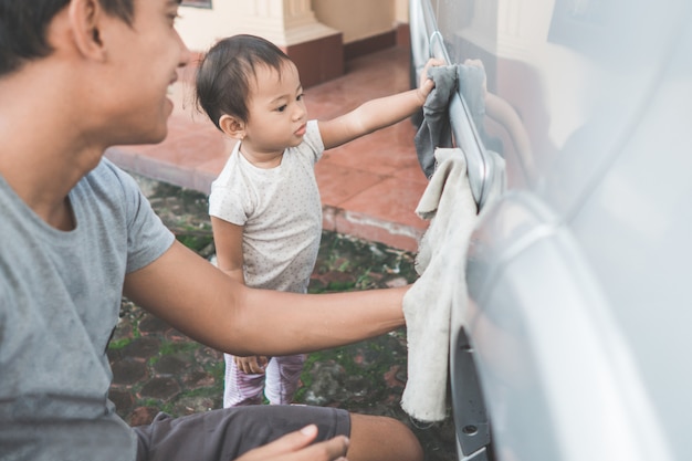 Enfant aidant son papa à nettoyer la voiture