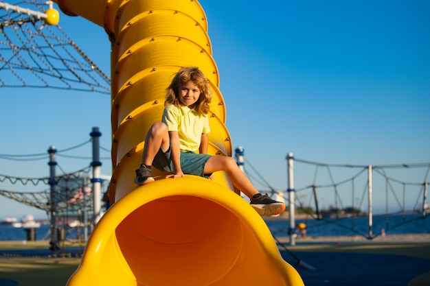 Enfant sur aire de jeux toboggan. Enfant mignon drôle s'asseoir sur le toboggan du tunnel sur l'aire de jeux.