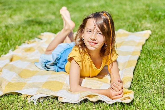 Enfant allongé sur la couverture sur l'herbe au soleil jour petite fille prendre des bains de soleil sur l'arrière-cour de la maison lors d'une journée d'été ensoleillée vacances d'été