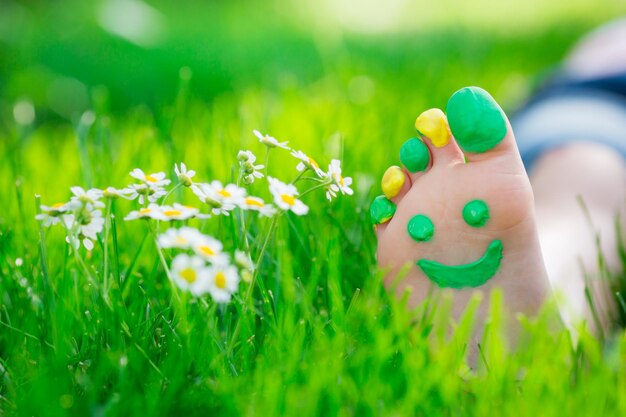 Enfant allongé sur l'herbe verte. Enfant s'amusant à l'extérieur dans le parc du printemps