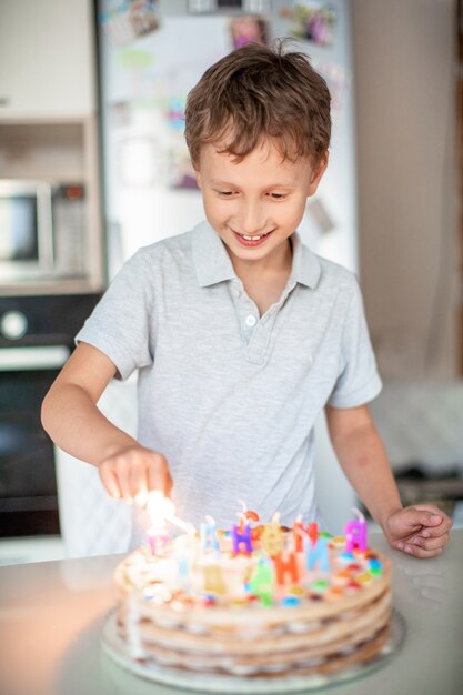 Enfant allume des bougies sur un gâteau d'anniversaire. Fête d'anniversaire à la maison. européen