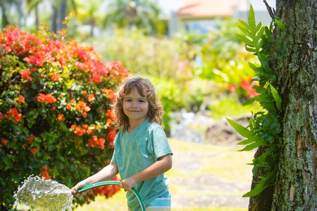 Enfant américain jouant avec un tuyau de jardin dans l'arrière-cour drôle enfant excité s'amusant avec un jet d'eau