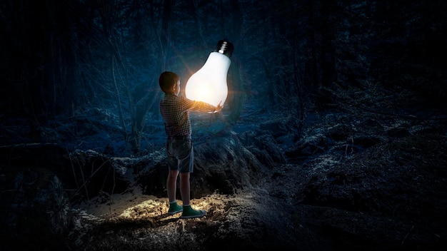 Enfant avec une ampoule rougeoyante dans l'obscurité. Technique mixte