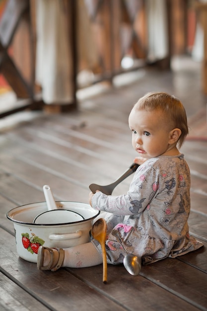 Un enfant d'un an joue sur un sol en bois avec des ustensiles de cuisine 3450