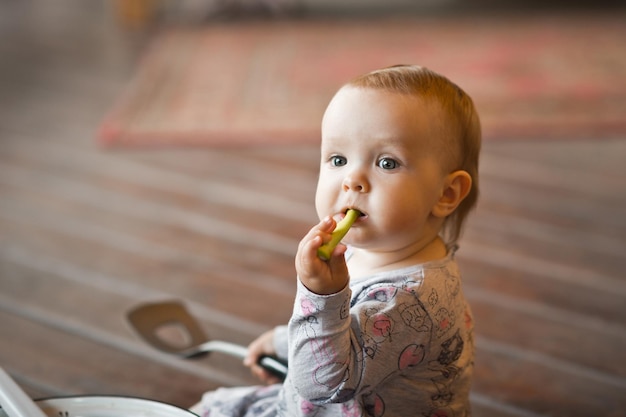 Un enfant d'un an joue sur un sol en bois avec des ustensiles de cuisine 3453