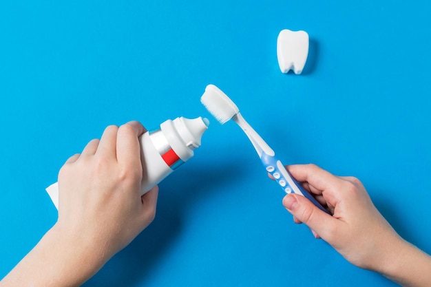 Un enfant applique du gel dentifrice sur une brosse à dents en silicone. Moyens de prendre soin de la cavité buccale.