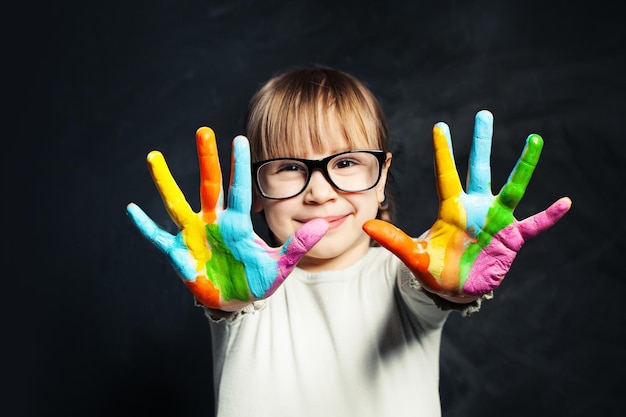 Photo un enfant apprécie sa peinture une fille mignonne avec des mains colorées sur le tableau de la salle de classe