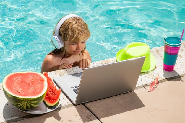 Enfant apprenant un ordinateur portable en ligne Enfant se détendre et se reposer sur un anneau gonflable coloré à l'aide d'un ordinateur dans la piscine Affaires et technologie d'été Voyages d'été