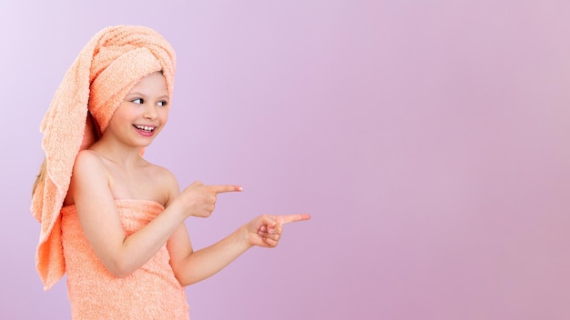 Un enfant après une douche Une petite fille enveloppée dans une serviette après avoir pris un bain montre une publicité sur un fond isolé