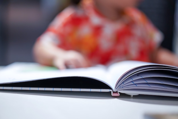 Enfant asiatique concentré lire un livre fermer le livre sur les enfants flous blancs à l'arrière-plan