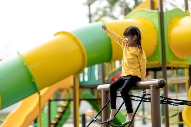 Enfant asiatique fille jouant sur l'aire de jeux dans le parc extérieur Moment heureux et bonne émotion