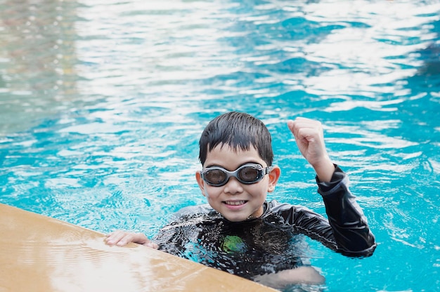 Un enfant asiatique heureux jouant au slider dans la piscine.