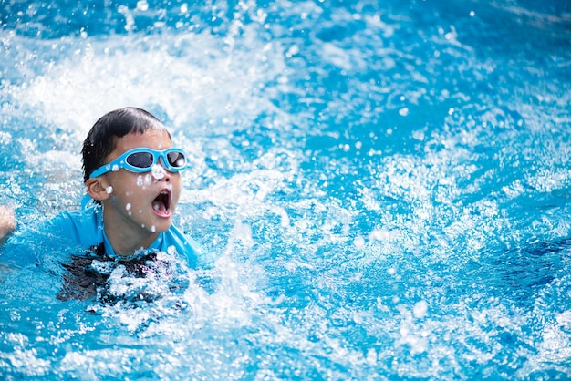 Enfant asiatique heureux avec des lunettes de natation dans la piscine.