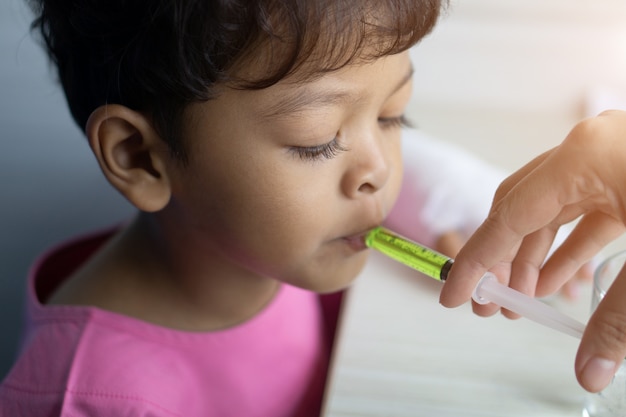 Un enfant asiatique malade mange un médicament à partir d&#39;une seringue en plastique