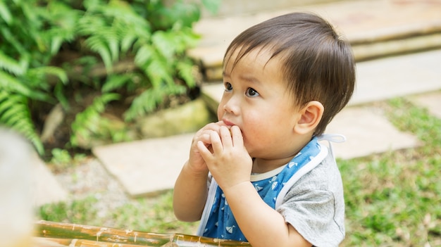 Enfant asiatique mignon mangeant une collation dans un jardin.