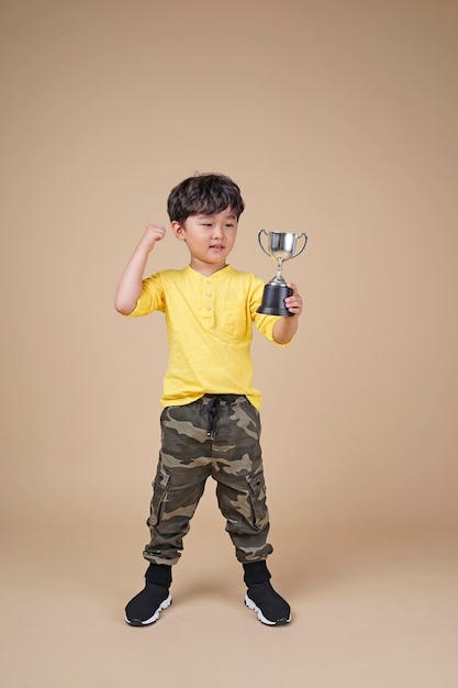 Enfant asiatique mignon tenant un trophée