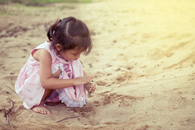 Enfant asiatique mignonne petite fille jouant avec du sable dans la cour de récréation