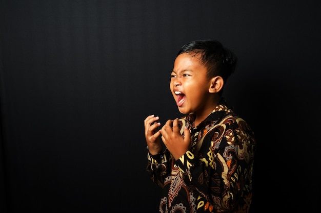 Photo un enfant asiatique portant batik crie isolé sur fond noir