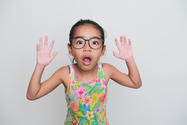 Enfant asiatique portant des lunettes montrant une drôle d'expression de visage choqué en regardant la caméra