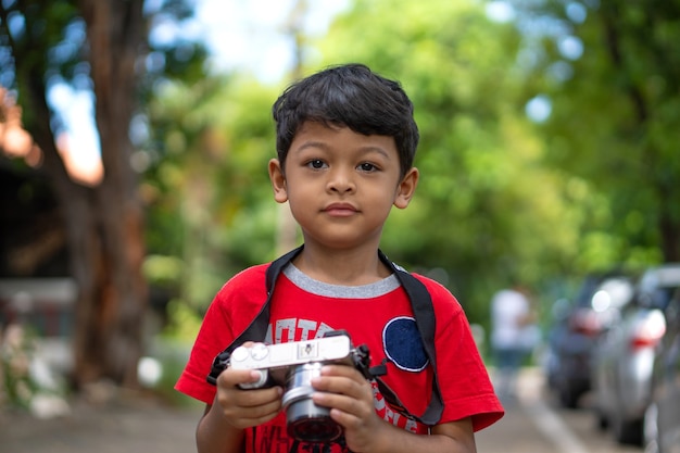 Enfant asiatique utilise un appareil photo numérique en prenant des photos dans un parc public