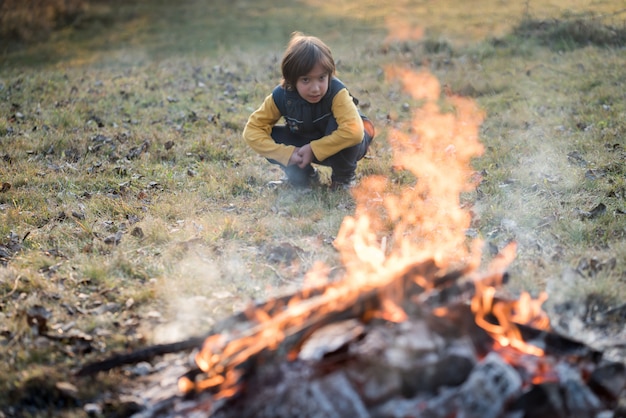 Enfant assis à côté du feu de camp sur Prairie