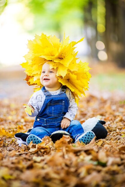 un enfant assis dans des feuilles jaunes