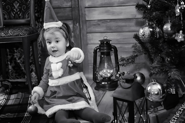 Un enfant assis devant un sapin de Noël attend le Père Noël